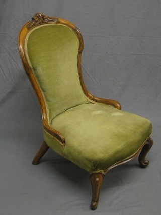 A Victorian walnut show frame nursing chair with carved cresting rail, upholstered in green Dralon (break to frame)