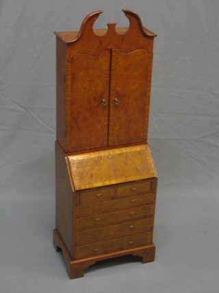 A Georgian style miniature walnut bureau bookcase with crossbanded top, the fall front revealing well fitted interior above 2 short and 4 long drawers, raised on bracket feet 13"