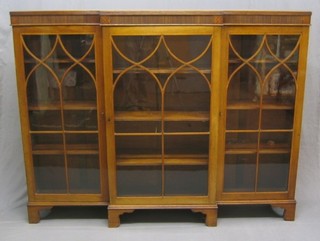 An Edwardian Sheraton style mahogany break front bookcase, the interior fitted adjustable shelves enclosed by astragal glazed panelled doors, raised on bracket feet 66"