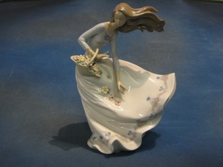 A Nao figure of a standing lady with basket of flowers and full length dress on a windy day, base marked 6767, 11" (slight chip to flower)
