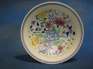 A circular Poole Pottery plate with floral decoration, the reverse marked BMK 11"