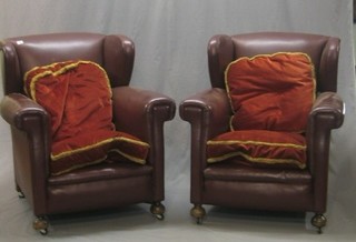 A pair of mahogany wing armchairs upholstered in red leather