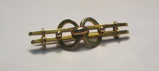 A gold bar brooch in the form of a bow