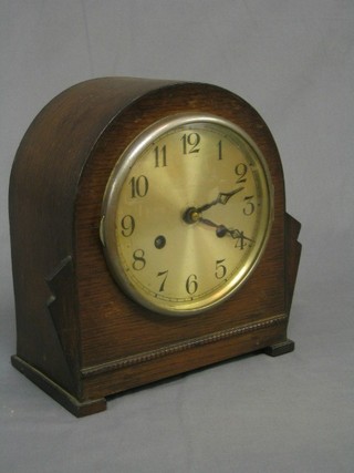 A 1930's 8 day striking mantel clock with silvered dial and Arabic numerals contained in an arched oak case