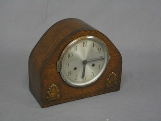 A 1930's striking mantel clock with silvered dial contained in arch shaped oak case