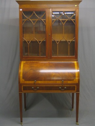 A handsome 20th Century Sheraton style cylinder bureau bookcase, the upper section with moulded cornice, the interior fitted adjustable shelves enclosed by astragal glazed panelled doors, the cylinder fall revealing a well fitted interior with pigeon holes and drawers, the base fitted 1 long drawer, raised on square tapering supports ending in spade feet, 40"