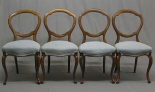 A set of 4 Victorian walnut balloon back dining chairs with shaped mid rails and seats of serpentine outline, raised on French cabriole supports