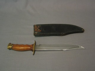 A reproduction Bowie knife 8 1/2" blade and wooden grip, contained in a black leather scabbard (some damage to blade) 