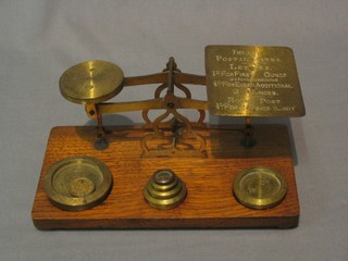 A pair of brass letter scales raised on an oak base complete with weights