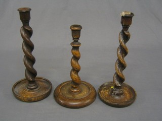 A pair of oak spiral turned candlesticks 12" and 1 other 10"