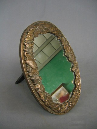 An oval Eastern easel mirror contained in a "copper" frame decorated storks 13"