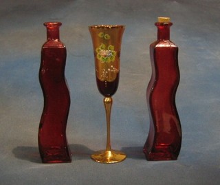 A ruby glass flute with gilt decoration and 2 shaped glass bottles 10"