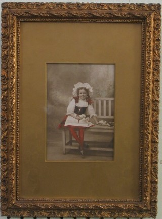 A 1930's enhanced photograph of a seated child on bench contained in a decorative gilt frame 5" x 4"