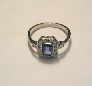 A lady's gold dress ring set a square cut sapphire supported by numerous diamonds and with baguette cut diamonds to the shoulder