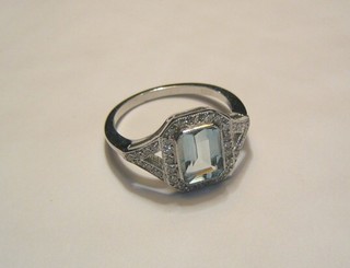 A lady's 18ct white gold dress ring set a rectangular cut aquamarine supported by numerous diamonds