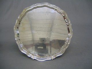 A circular engraved silver salver with bracketed border, raised on scrolled feet, Sheffield 1939, 15 ozs
