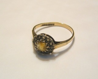 A gold ring set an amber coloured stone surrounded by white stones