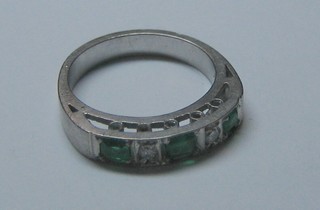 A white metal dress ring set 2 diamonds interspaced by "emeralds"