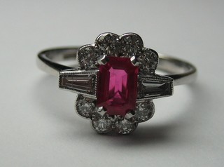 A lady's 18ct white gold dress ring set a rectangular cut ruby surrounded by 8 diamonds and with baguette cut diamonds to the shoulders