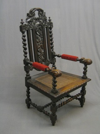 A Victorian oak Carolean style high back open arm chair with woven cane seat, raised on spiral turned supports united by a stretcher