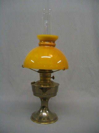 A 20th Century brass oil lamp with clear glass chimney and amber shaped
