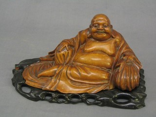 An Eastern carved figure of a reclining Buddha, raised on a hardwood stand 13"