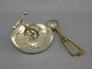 A circular silver plated nut cracker and stand and an ice cream scoop