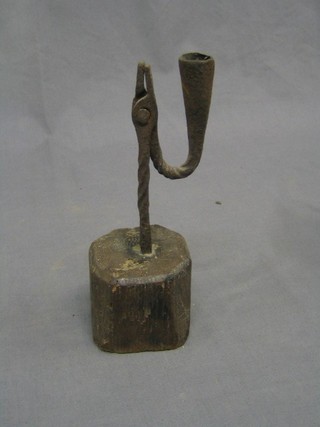 A 17th/18th Century iron rush light holder, raised on a weathered elm block