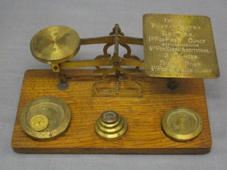 A pair of brass letter scales raised on an oak base complete with weights