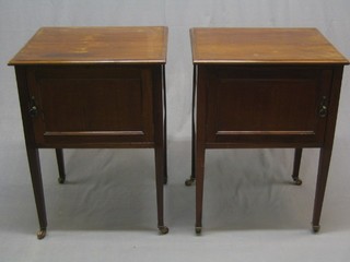 A pair of Edwardian mahogany bedside cabinets enclosed by panelled doors and raised on square tapering supports 22"