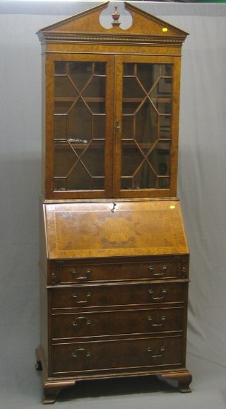 A handsome 20th Century Queen Anne style figured walnut bureau bookcase, the upper section with broken pediment and dentil cornice, the interior fitted adjustable shelves enclosed by astragal glazed panelled doors, the fall front revealing a well fitted interior above 4 long graduated drawers, raised on ogee bracket feet 29"