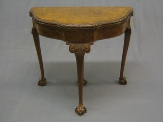 A 1930's figured walnut Queen Anne style card table, carved throughout and raised on cabriole, ball and claw supports 33"