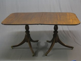 A 20th Century reproduction Georgian style mahogany D end twin pillar dining table with crossbanded top, having 1 extra leaf and raised on turned tripod supports