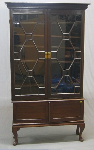A Georgian mahogany bookcase top with moulded and dentil cornice, the interior fitted adjustable shelves enclosed by astragal glazed panelled doors, raised on a later base fitted a cupboard enclosed by double cupboards, raised on cabriole supports 41"