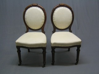 A pair of Victorian mahogany balloon back dining chairs with seats of serpentine outline, raised on turned and fluted supports, upholstered in white hide