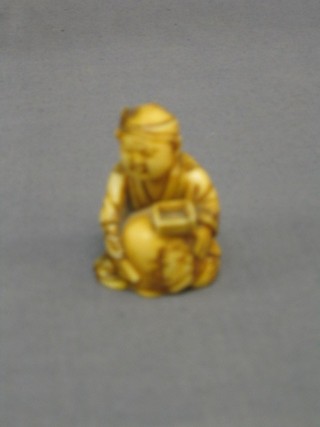 A 19th Century Japanese carved ivory Netsuke of a seated boy with square plate and bundle 2"