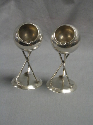 A pair of Art Deco silver plated golfing ashtrays in the form of golf balls supported by 3 clubs