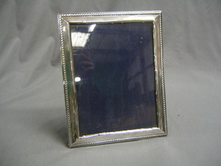 An embossed silver easel photograph frame with ribbon border, 9" x 7 1/2", Birmingham 1909