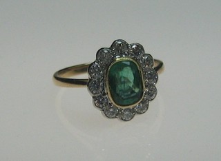 A lady's 18ct gold dress ring set an oval cut emerald surrounded by 12 diamonds (approx 0.53/1.0ct)