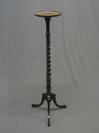 An Edwardian mahogany torchere raised on a spiral turned column with tripod base   