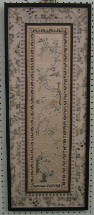 A 19th/20th Century Oriental silk panel with floral decoration, depicting birds amidst branches 26" x 10" contained in an ebony frame