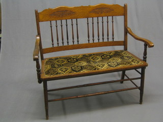 An Edwardian oak double chair back settee with bobbin turned decoration, raised on turned supports