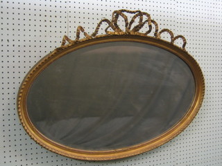 A 19th/20th Century oval plate wall mirror contained in a decorative gilt frame surmounted by a garland of ribbons 32"