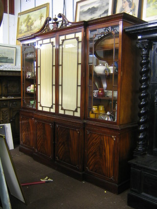 A good quality Georgian style mahogany break front bookcase on cabinet with pierced broken pediment