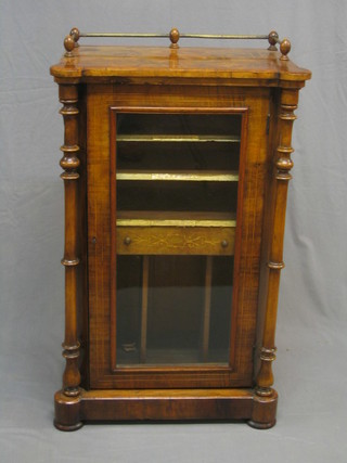 A Victorian inlaid figured walnut music cabinet with brass railed top, the interior fitted shelves enclosed by a glazed panelled door flanked by a pair of columns 24"