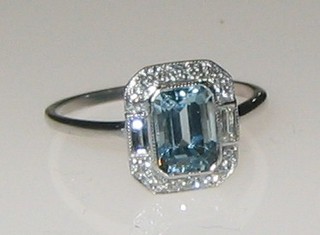 A lady's 18ct white gold dress ring set a rectangular cut aquamarine supported by 2 baguette cut diamonds and numerous diamonds to the shoulders