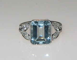 A lady's 18ct gold dress ring set a square cut aquamarine supported by numerous diamonds to the shoulders