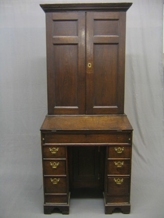 A Queen Anne Country oak kneehole pedestal bureau bookcase, the raised back with moulded cornice, fitted a cupboard with shelved interior enclosed by panelled doors, the rising fall front fitted a well with pigeon holes, the kneehole base fitted a cupboard flanked by 6 short drawers, raised on bracket feet 30"