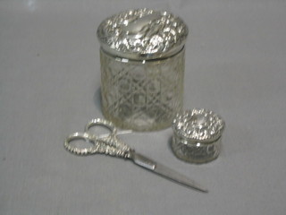 A circular cut glass dressing table jar 3" with embossed silver lid, a circular rouge pot with embossed silver lid and a pair of silver handled scissors