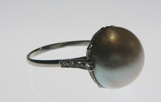 A lady's platinum or white gold dress ring set a large pearl supported by diamonds